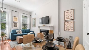 Una sala de estar moderna con un sofá azul, una mesa de centro de vidrio y una chimenea.