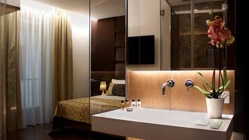 A modern hotel room with a large bed, a bedside table, a white sink, and a mirror.