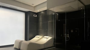 A modern spa room with a massage chair, a glass shower enclosure, and a large window. - PALAZZO CARTARI (Palermo)