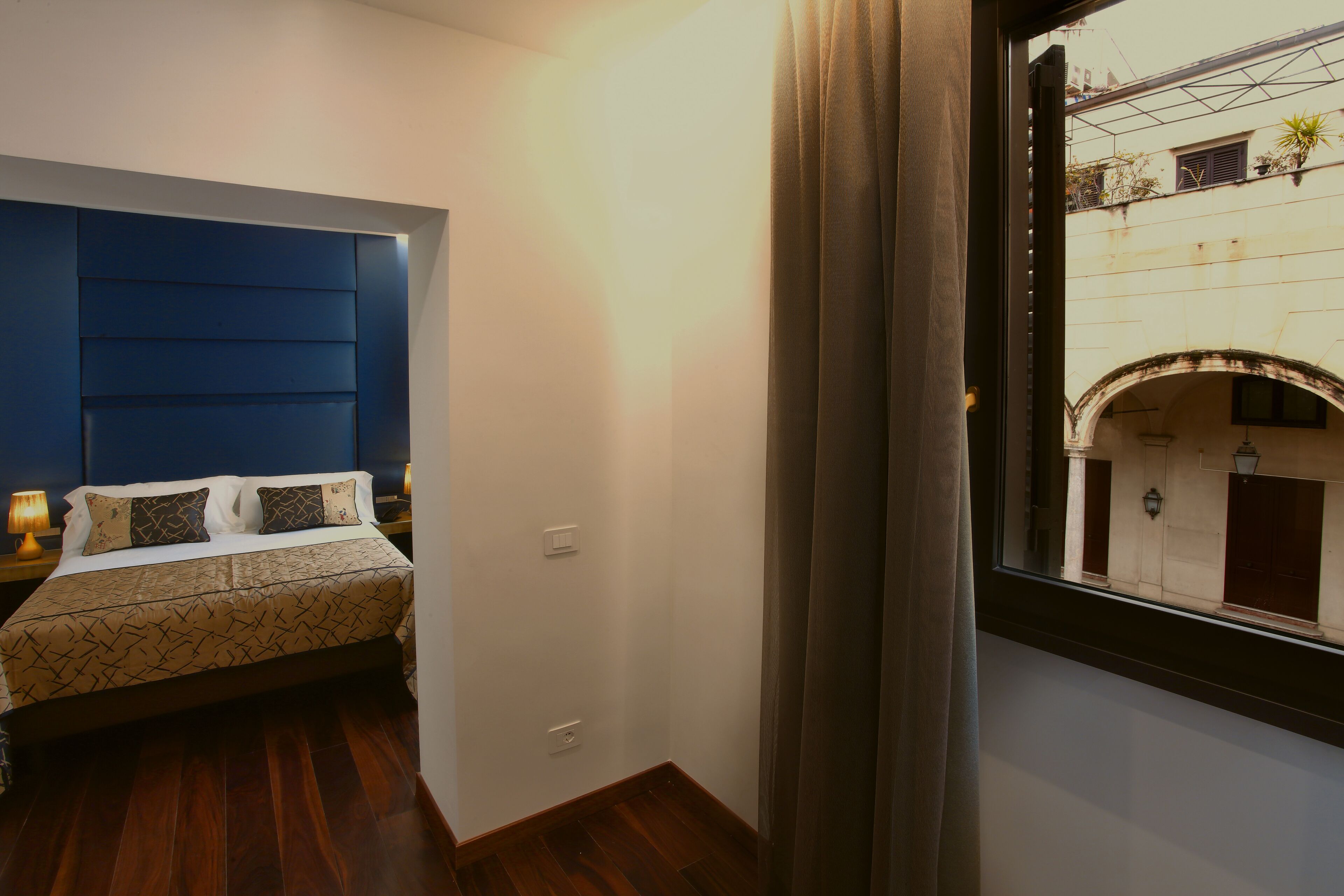 Une chambre à coucher avec un lit, une table de chevet et une fenêtre avec des rideaux.