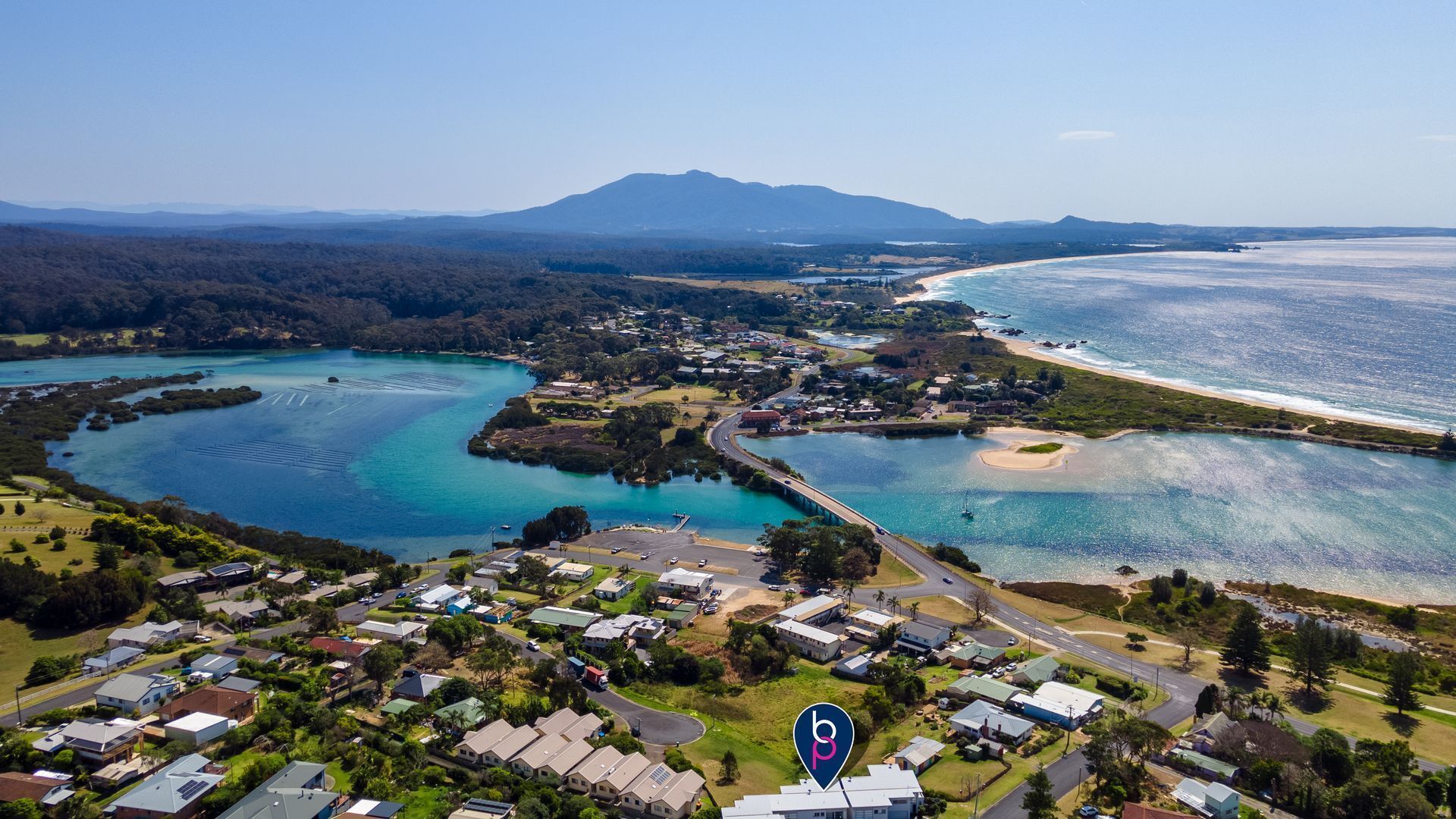 Vue aérienne d’une ville côtière avec des zones résidentielles, une plage et une baie.