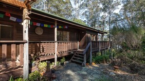 A wooden cabin with a wooden deck and a staircase leading to a second level. - 129 Murrah Street - River Views (Bermagui)
