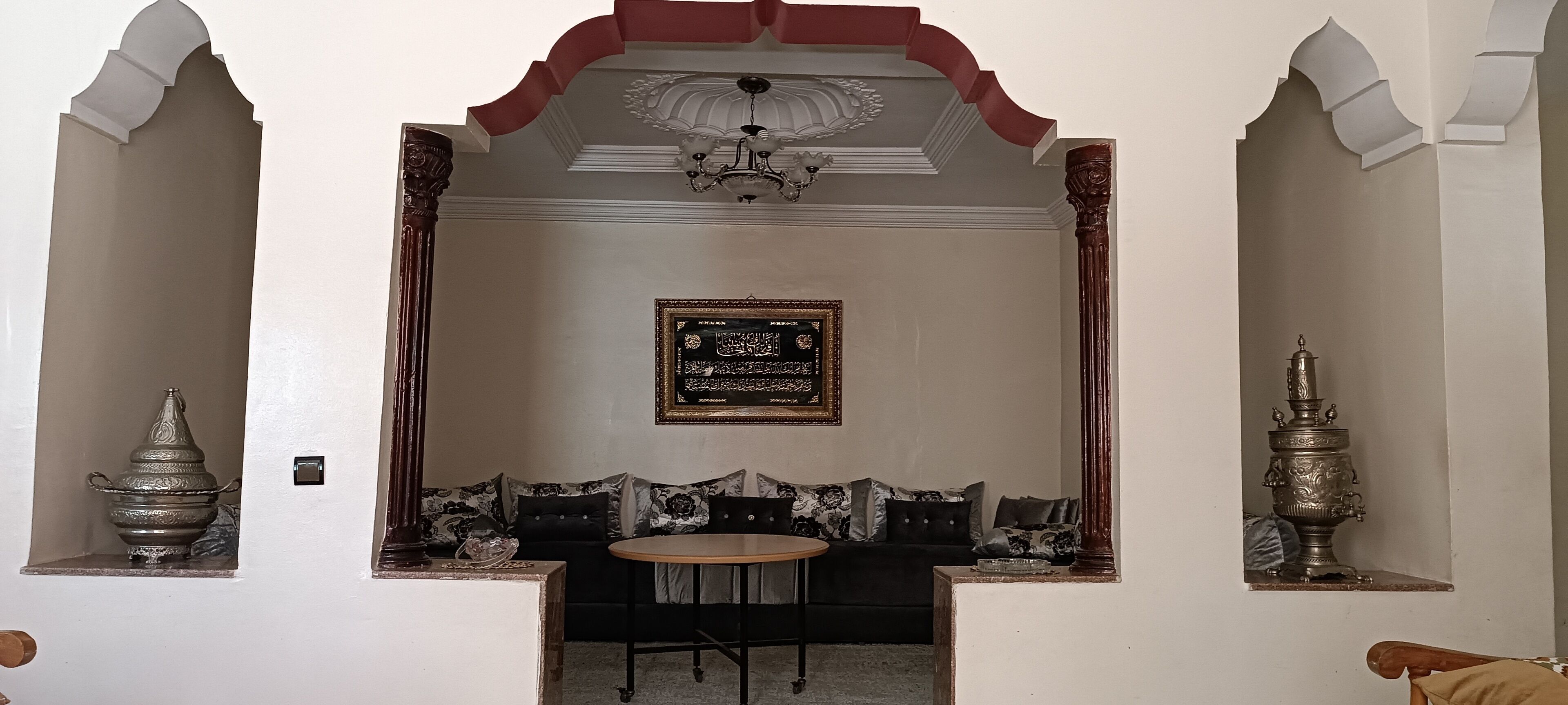 Une pièce au décor traditionnel, avec un ensemble de canapés, une petite table ronde et des objets décoratifs accrochés aux murs.