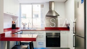 A modern kitchen with white cabinets, a red countertop, a stainless steel range hood, and a built-in oven. - Cozy Apartment in Sitges (Sitges)