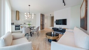 A modern living room with a dining area, a kitchen, and a TV mounted on the wall. - Apartamenty Sun & Snow Porto (Gdansk)