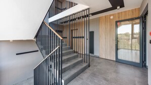 A modern staircase with metal railings and wooden accents, leading to a door with a glass panel. - Apartamenty Sun & Snow Porto (Gdansk)