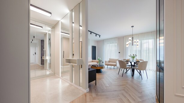 A modern living room with a dining area, featuring a herringbone wood floor, a round coffee table, and a sofa. - Apartamenty Sun & Snow Porto (Gdansk)