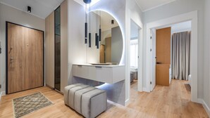 A modern bathroom with a large mirror, a sink, and a toilet. There is a bench in the corner and a shower area visible through a glass door. - Apartamenty Sun & Snow Porto (Gdansk)