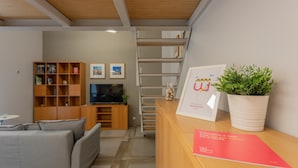 A reception area with a wooden desk, a grey sofa, a bookshelf, and a TV.