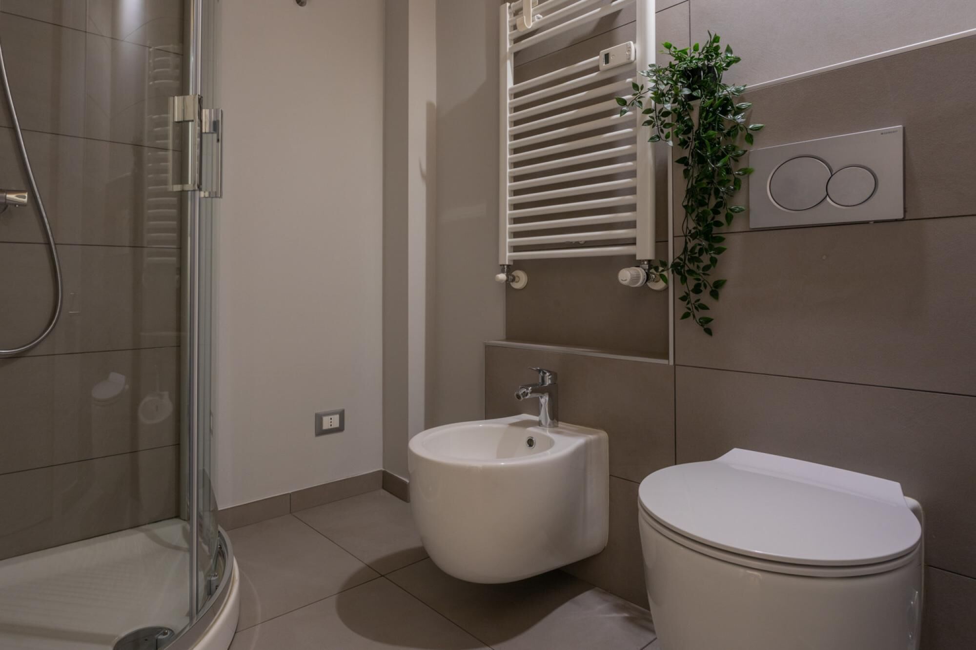 Et moderne badeværelse med et glasbadeværelsesafskærmning, en bidet og et toilet.