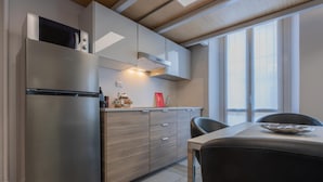 A modern kitchen with a stainless steel refrigerator, wooden cabinets, and a dining area with a table and chairs.