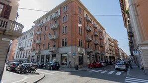 A multi-story building with balconies, a parking sign, and a pedestrian crossing.