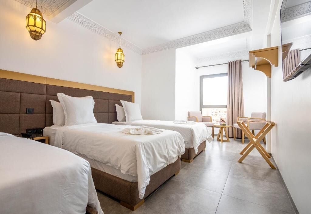 A hotel room with three beds, a desk, and a chair.