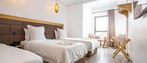 Una habitación de hotel con tres camas, un escritorio y una silla.