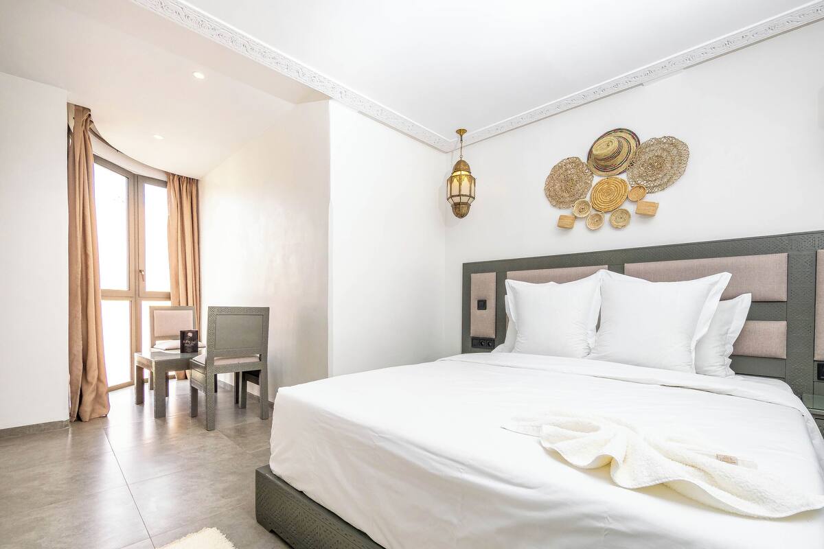 Moderni hotellihuone, jossa on suuri sänky, työpöytä ja tuoli.