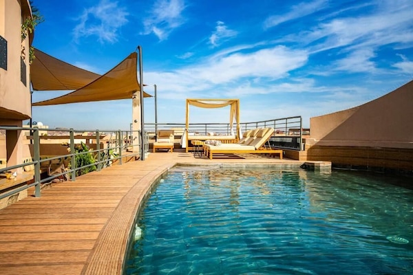 Een buitenzwembad, ligstoelen bij het zwembad