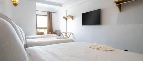 Een hotelkamer met twee bedden, een flatscreen televisie en een groot raam met gordijnen.