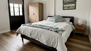 Un dormitorio con cama, armario, mesita de noche y dos cuadros en la pared.