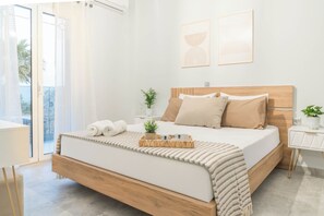 Un dormitorio moderno con una cama de madera, una mesita de noche, una planta pequeña y vistas a través de un ventanal.
