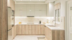 A modern kitchen with wooden cabinets, stainless steel appliances, and a white countertop. - Dafni Villa, A place to visit (Rethymno)