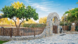 A stone pathway leading to a stone archway, surrounded by a wooden fence and greenery. - Dafni Villa, A place to visit (Rethymno)