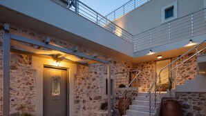 A modern building with a stone facade, a metal staircase, and a well-lit entrance. - Kedros Villa, A Luxury Touch (Rethymno)