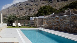 A swimming pool with a stone wall and a mountain in the background. - Kedros Villa, A Luxury Touch (Rethymno)