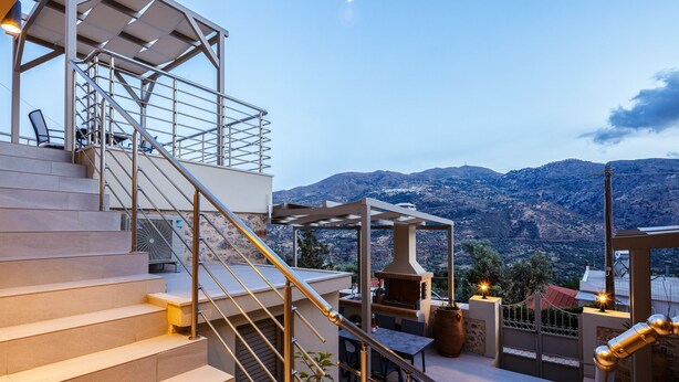 A staircase leading to a terrace with a barbecue area, outdoor seating, and a view of mountains. - Kedros Villa, A Luxury Touch (Rethymno)