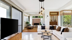 A spacious living room with a large flat-screen TV, a white sofa set, a coffee table, and a fireplace. - Rizes Villa with Jacuzzi & Heated Pool, A Nature Paradise! (Rethymno)