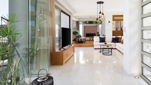 A modern living room with a TV, sofa, and dining area. - Rizes Villa with Jacuzzi & Heated Pool, A Nature Paradise! (Rethymno)