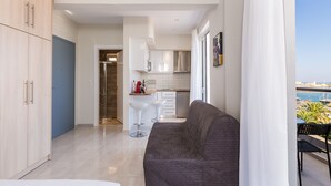 A modern apartment with a living area, kitchenette, and a balcony with a view of the sea.