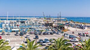 A marina with boats docked, a parking lot with cars, and a clear blue sky.