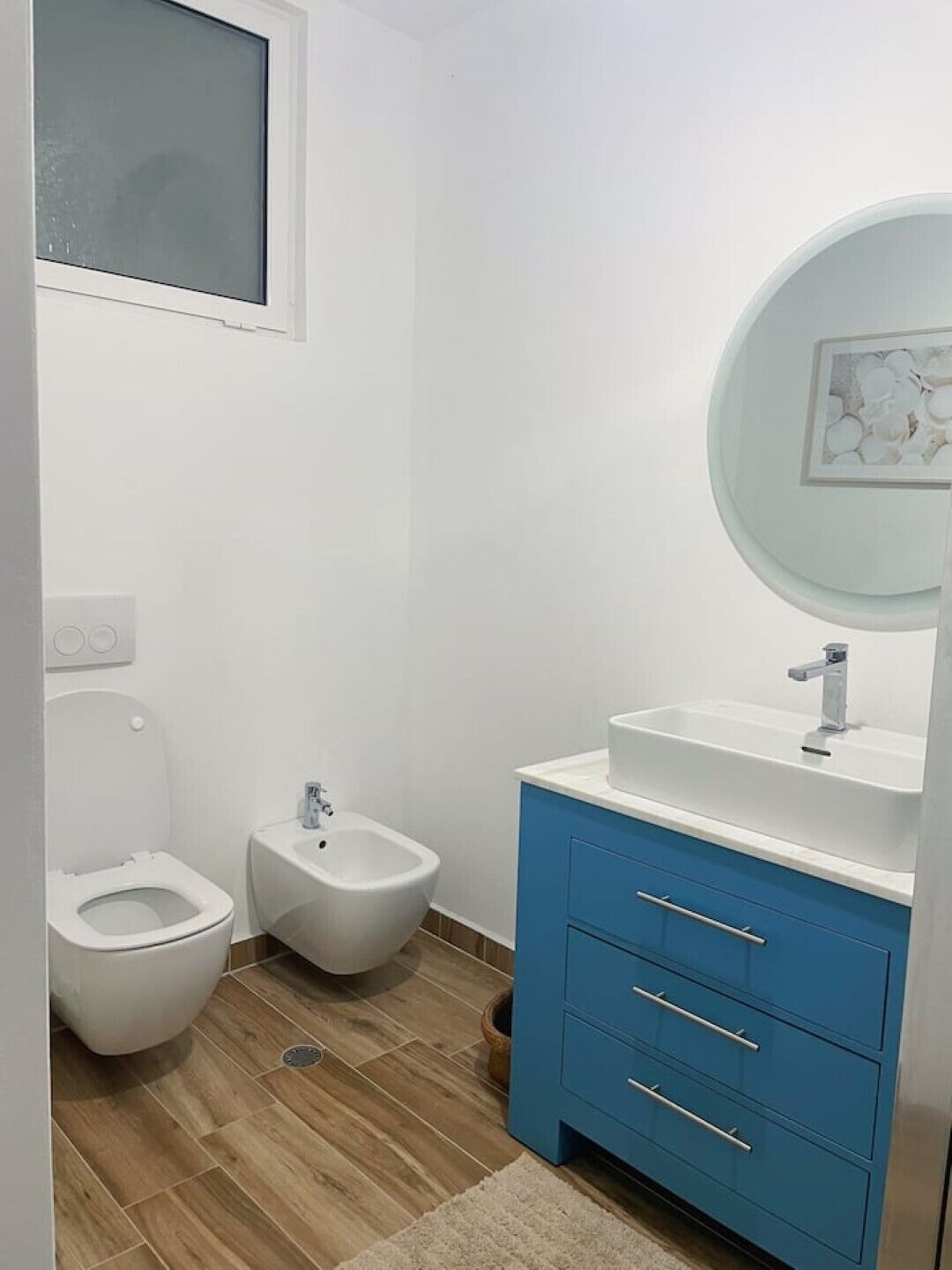 Un baño con inodoro, bidé y lavamanos con un armario azul.