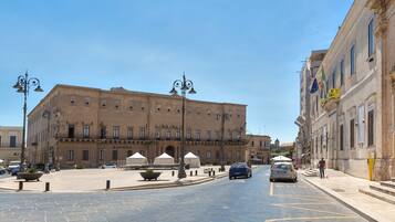 A historic building with a central courtyard, large windows, and a flag on the right.