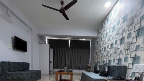 A modern living room with a marble floor, a ceiling fan, a flat-screen TV, and a patterned wall. - The Terra Hotel (Arpora)