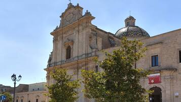 A historic building with a prominent bell tower and dome, surrounded by trees and a clear sky.