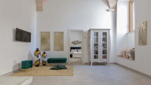 A spacious room with a high ceiling, a green velvet sofa, a beige rug, and a white cabinet with glass doors. - 3569 Le Dimore di Chez Papà - 4 by Barbarhouse (Manduria)