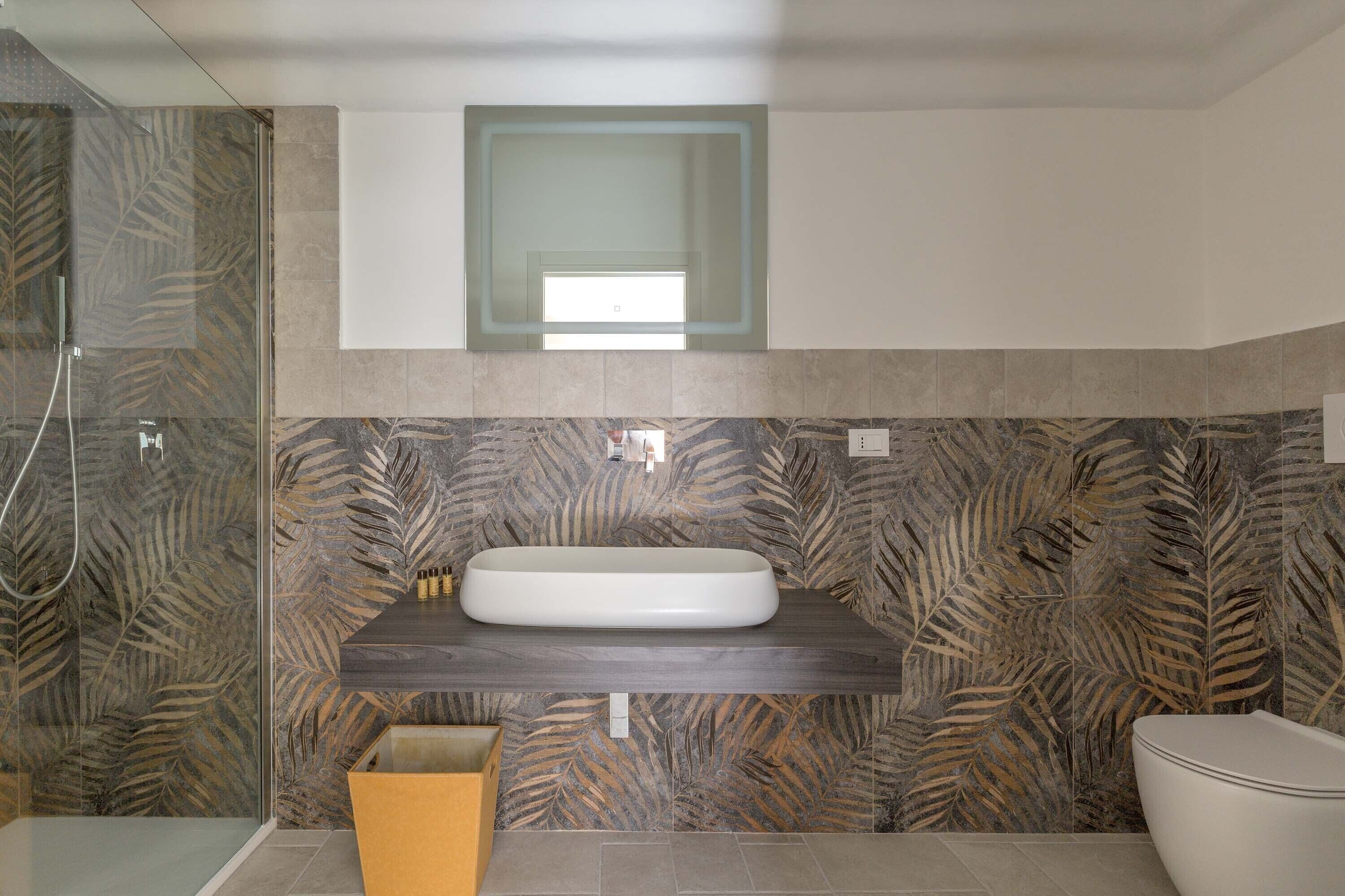 A modern bathroom with a large, oval sink, a glass shower enclosure, and a toilet.