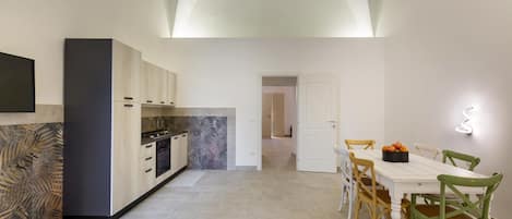 A modern kitchen with a dining area, featuring a large island, white cabinetry, and a tiled floor.