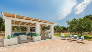 Eine Außenpatio mit Pergola, Sitzgelegenheit und Topfpflanzen.