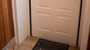A closed door with a welcome mat and a doorbell system.
