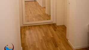 A hallway with wooden flooring and white walls, leading to a door at the end.