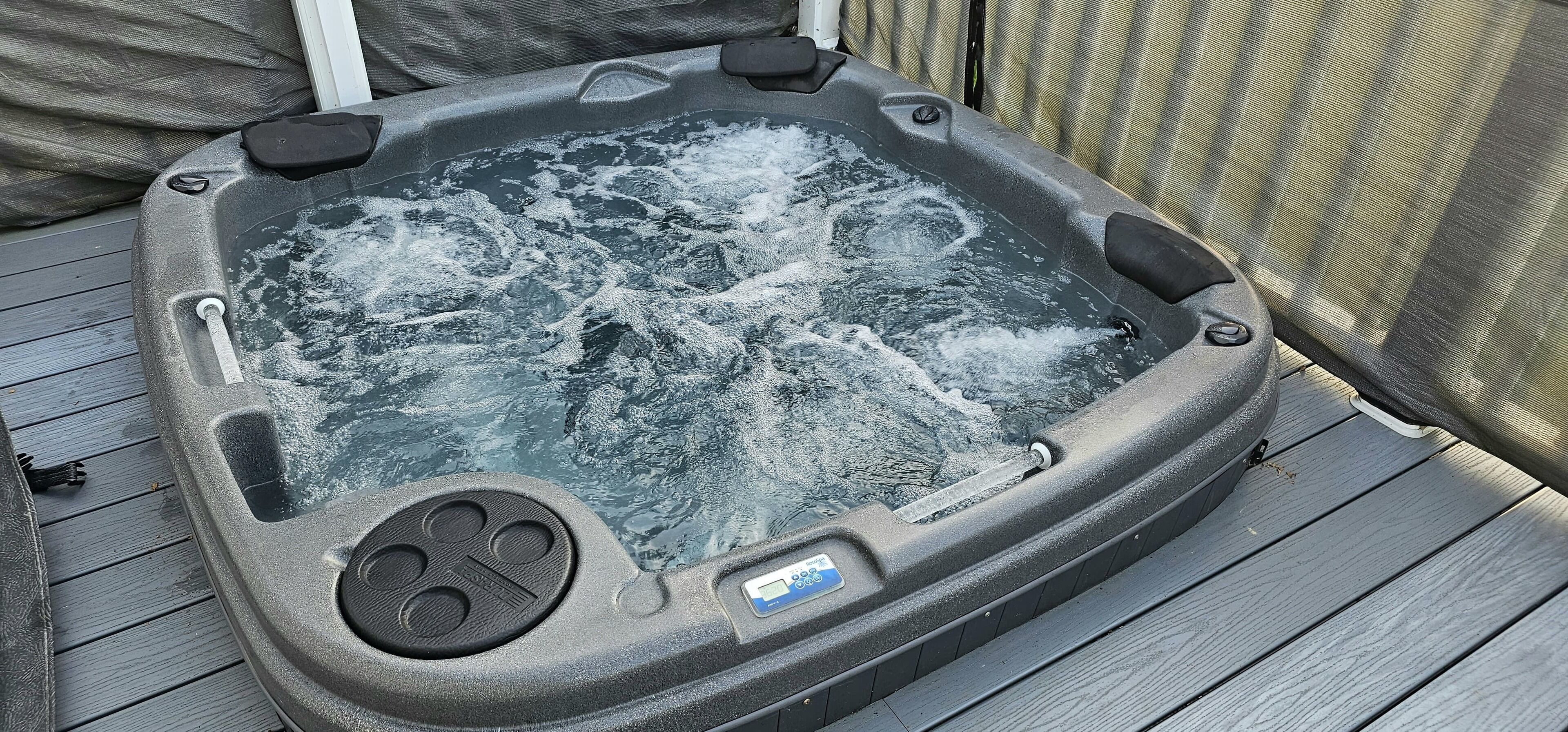 A hot tub with a control panel and a safety lock on the side.