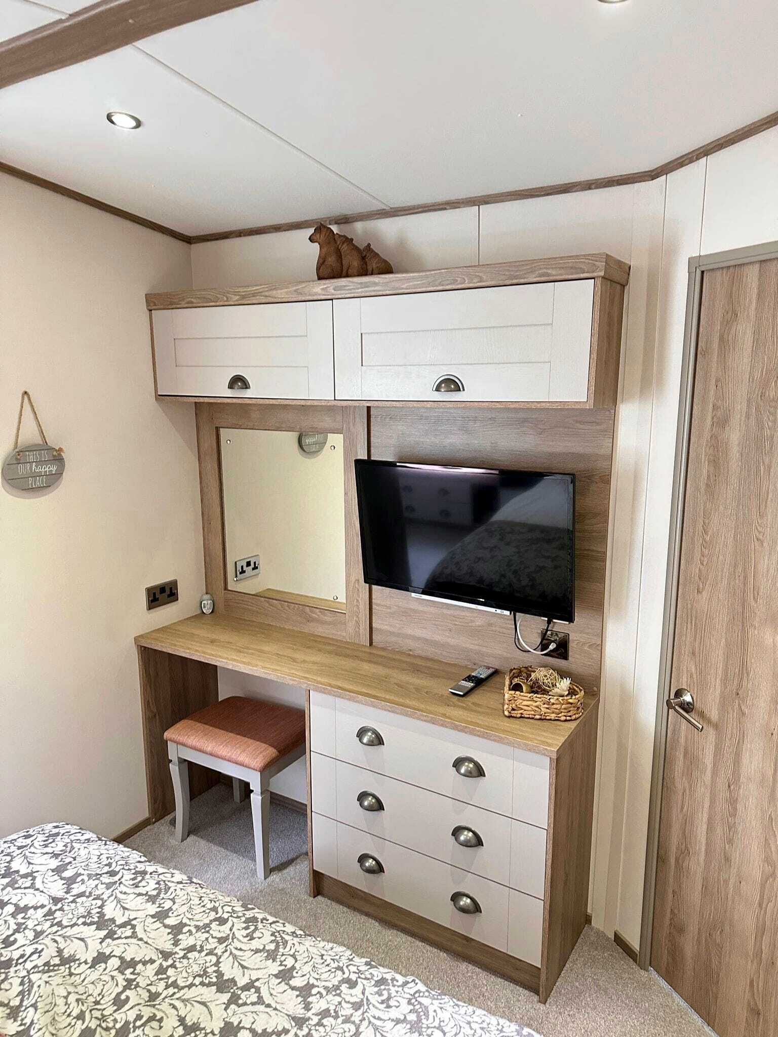 A bedroom with a wooden desk, a television, a bed, and a wardrobe.