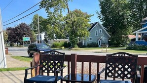 A wooden deck with two chairs and a table, overlooking a residential street.