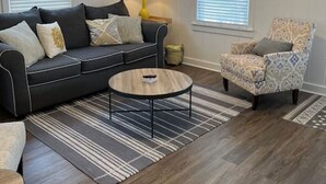 A living room with a dark-colored sofa, a patterned armchair, a round coffee table, and a ceiling fan.