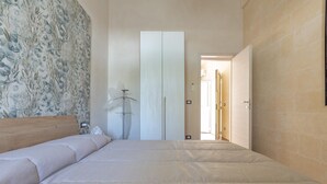Een slaapkamer met een groot bed, een garderobe en een lamp.