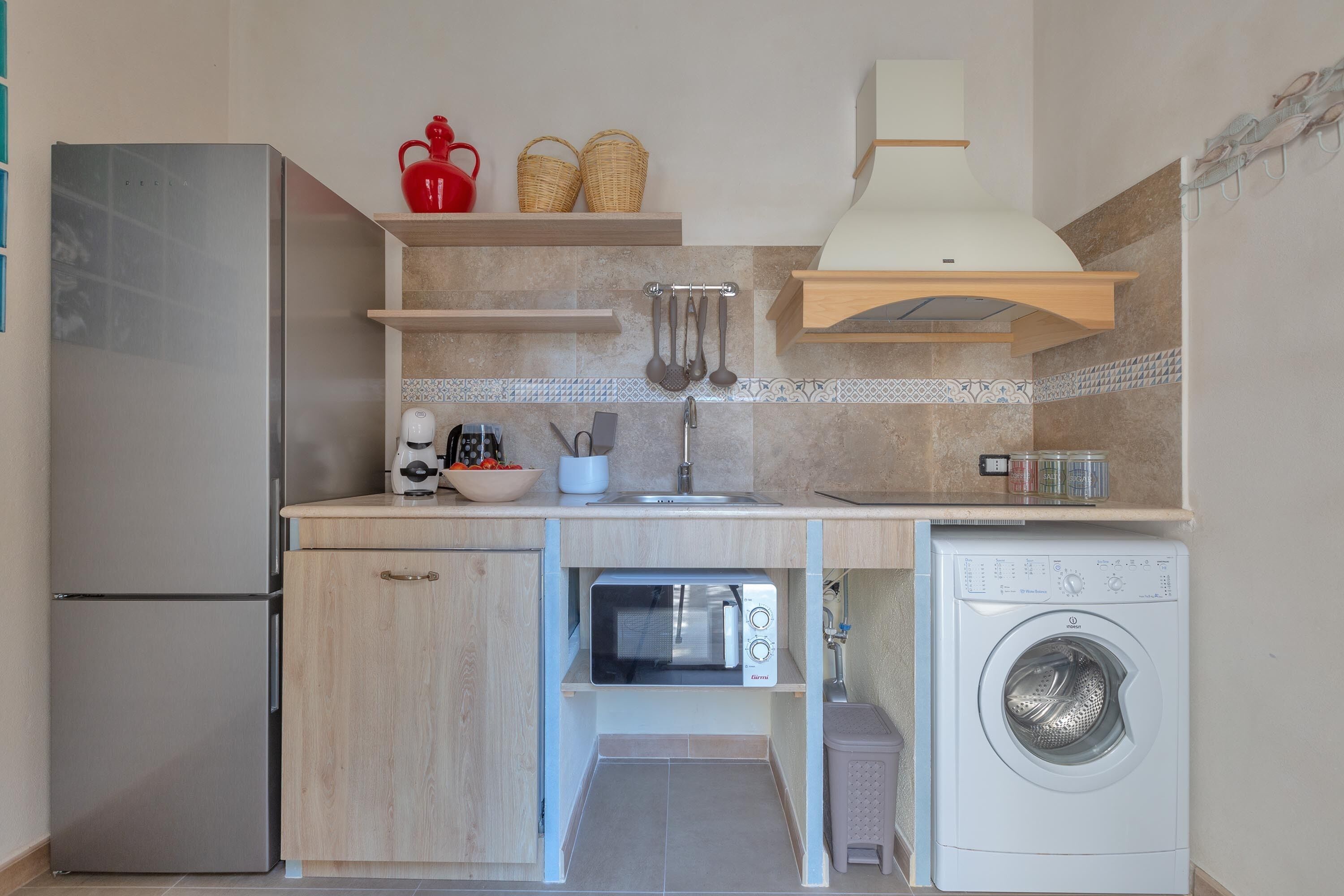 A compact kitchen with a built-in microwave, a washing machine, and a sink.