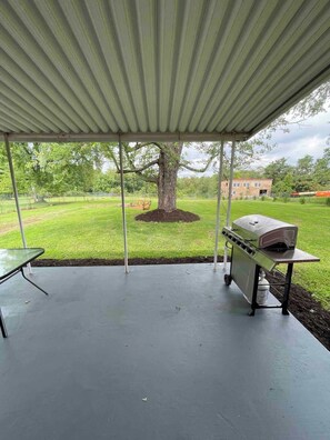 A covered patio area with a grill and a table. - Charming Farmhouse, entire home (Monaca)