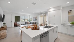 A modern kitchen with a large island, white cabinetry, and a built-in dishwasher. - Mountain view townhouse w/ fire pit & pool (La Quinta)